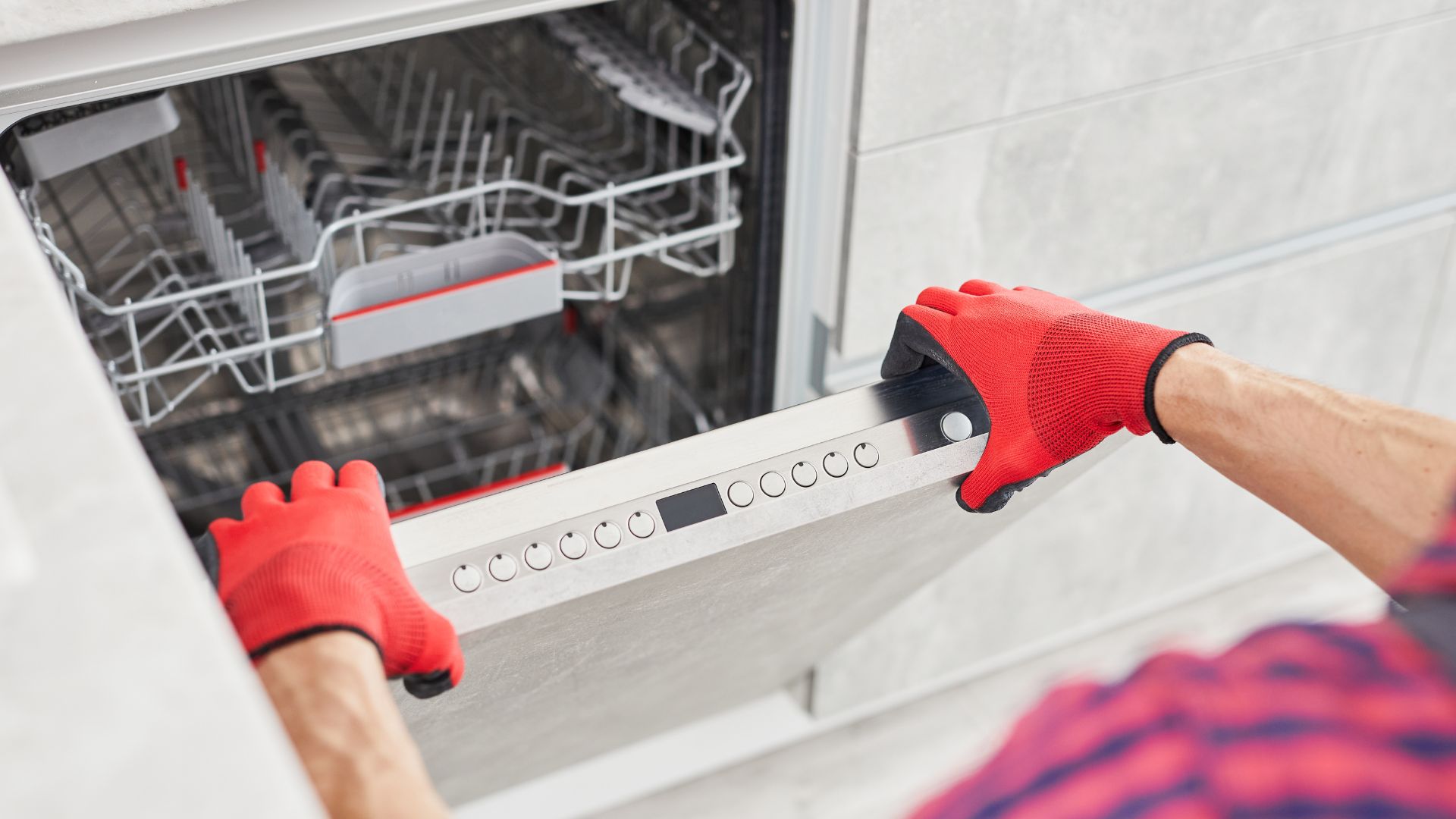 A man in red gloves is opening a dishwasher